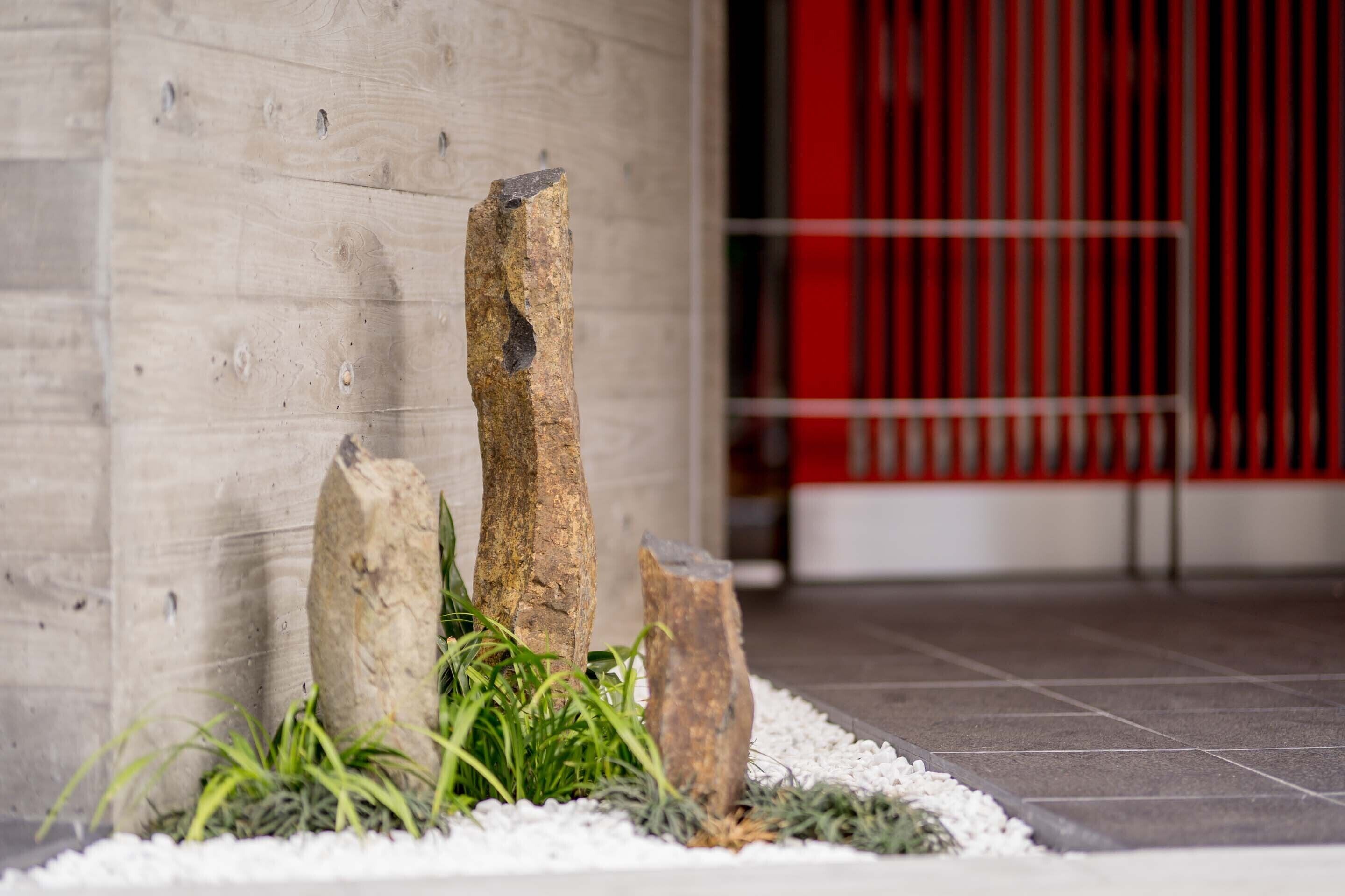 A stone wall with three upright stones and some greenery in front.