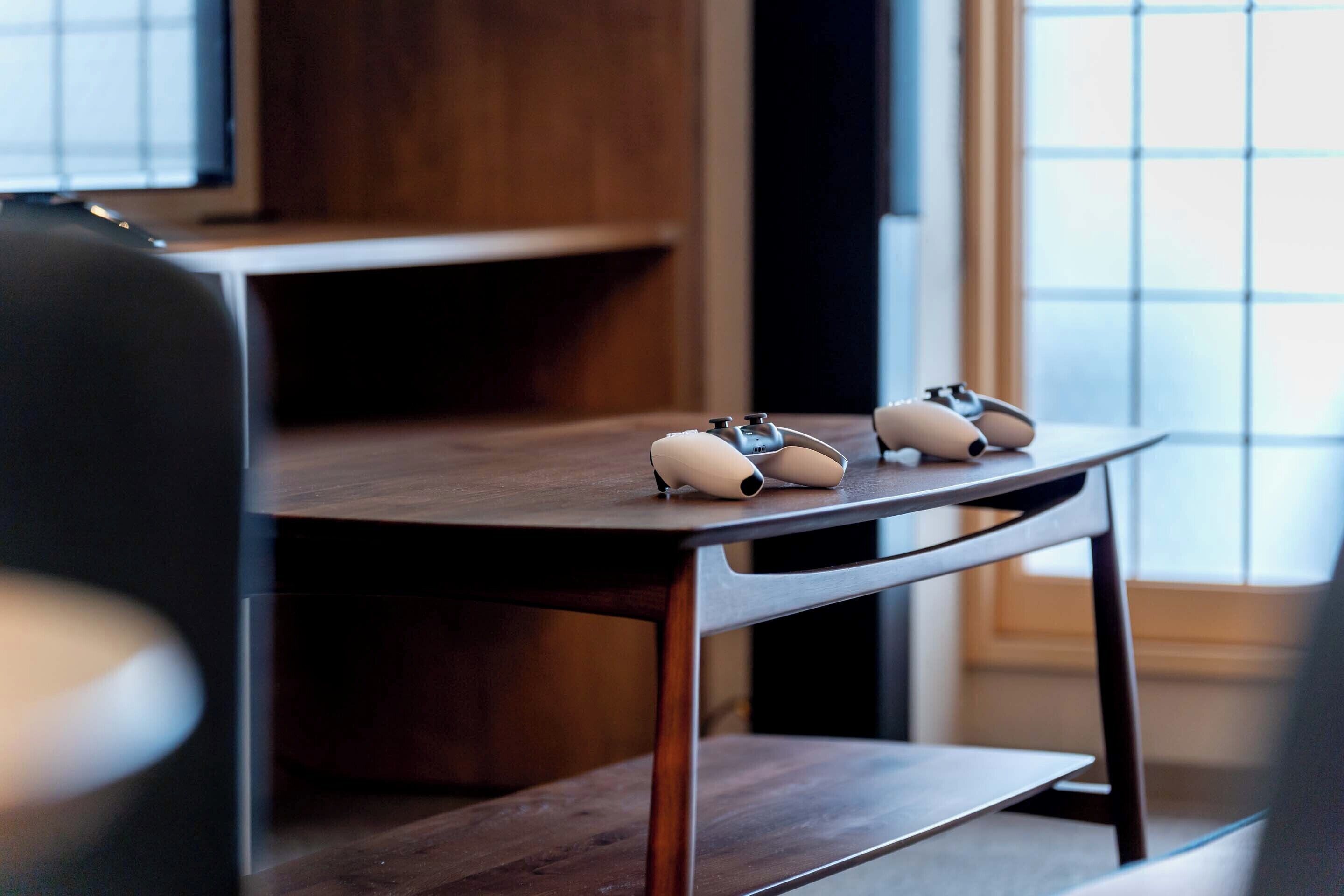 A wooden table with two white objects on it, a chair, and a window with blinds.