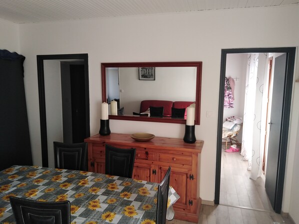Un comedor con una mesa dispuesta para dos, un aparador de madera y un espejo sobre la mesa.