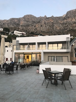 Un edificio moderno con una terrazza, sedute all'aperto e vista sulle montagne rocciose.