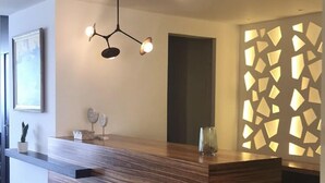 Un mostrador de recepción moderno con detalles de madera, una lámpara colgante y un panel decorativo en la pared.