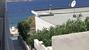Vista de una zona costera con cielo despejado, una antena parabólica en un edificio y una escalera que baja a un nivel inferior.