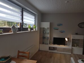 Un salon moderne avec un téléviseur, des étagères et une cheminée.