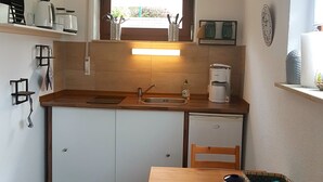 Una cocina compacta con encimera de madera, un lavamanos, una ventana con vistas, una mesa de comedor con sillas y un cubo de basura.