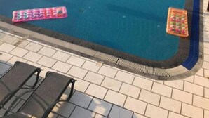 A swimming pool with lounge chairs and umbrellas, overlooking a body of water and mountains. - Elena Apartments (Kalymnos)