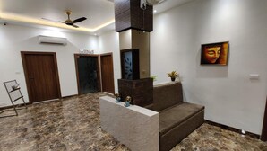 A modern lobby with marble flooring, a central seating area, and a ceiling fan. - La Imperio Hotel (Aligarh)