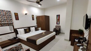A hotel room with a large bed, a desk with a computer, a chair, and a television. - La Imperio Hotel (Aligarh)