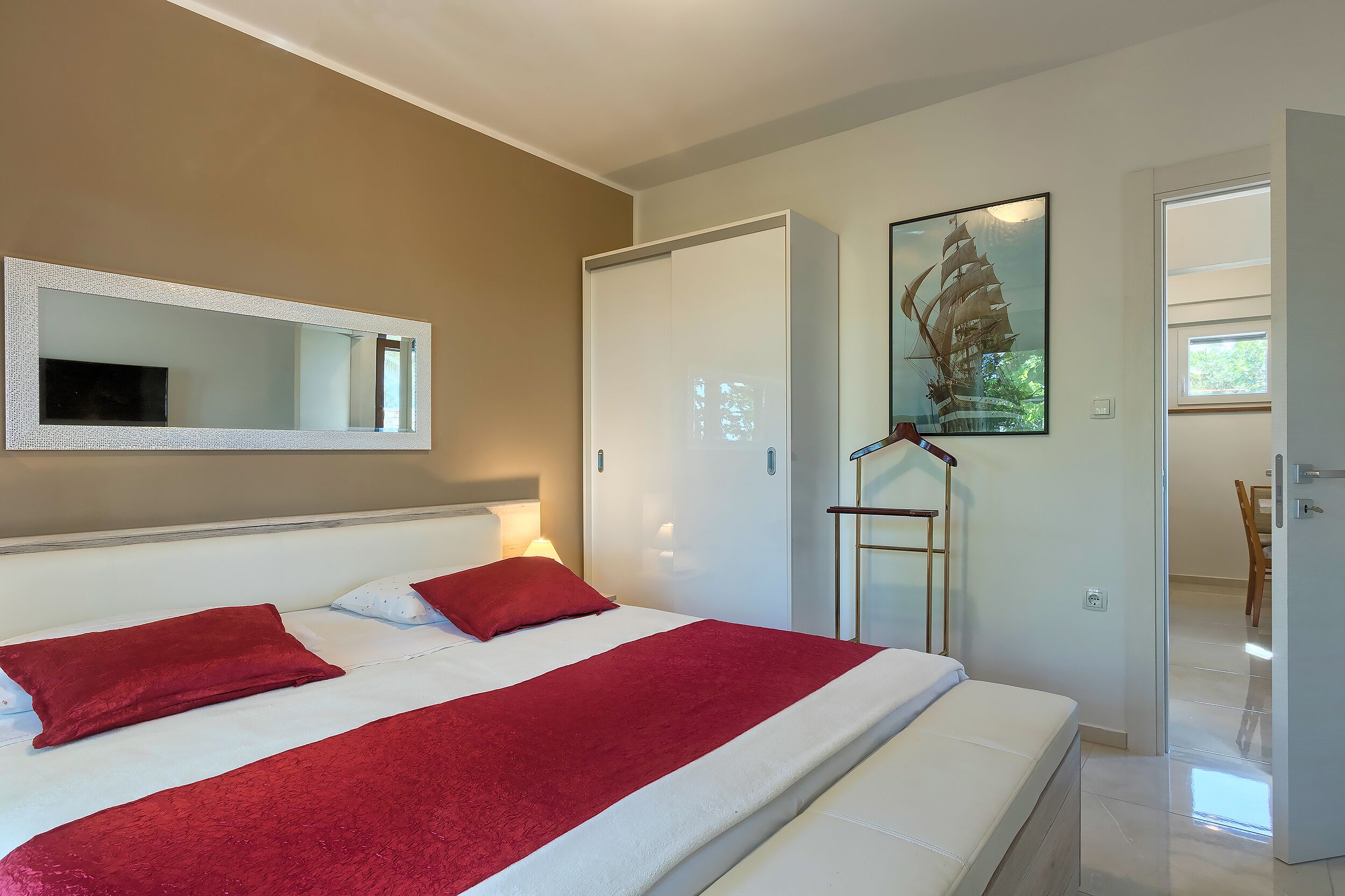 Une chambre à coucher avec un lit, un grand miroir, un tableau et une armoire.