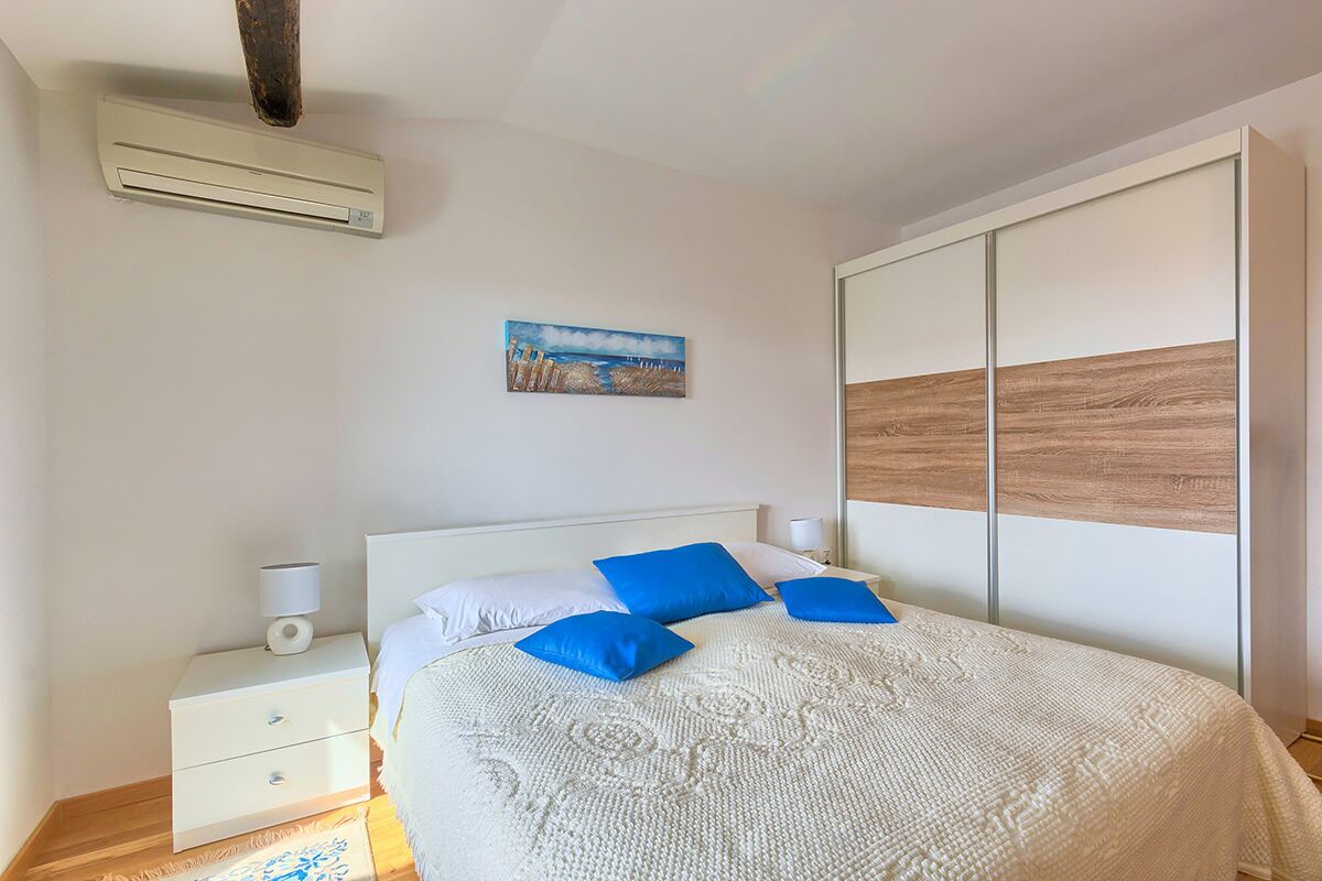 A bedroom with a bed, nightstands, a painting, and a wardrobe.