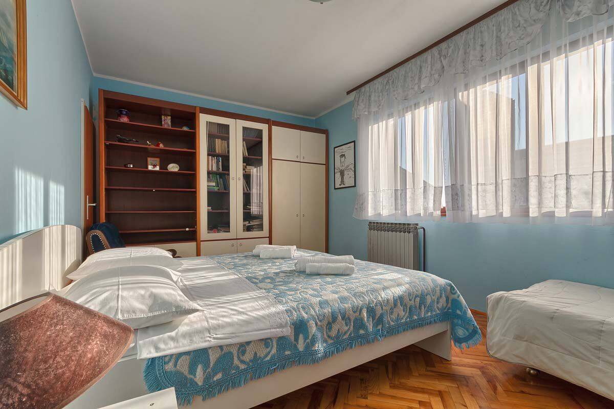 Un dormitorio con una cama grande, un armario y una ventana con cortinas ligeras.