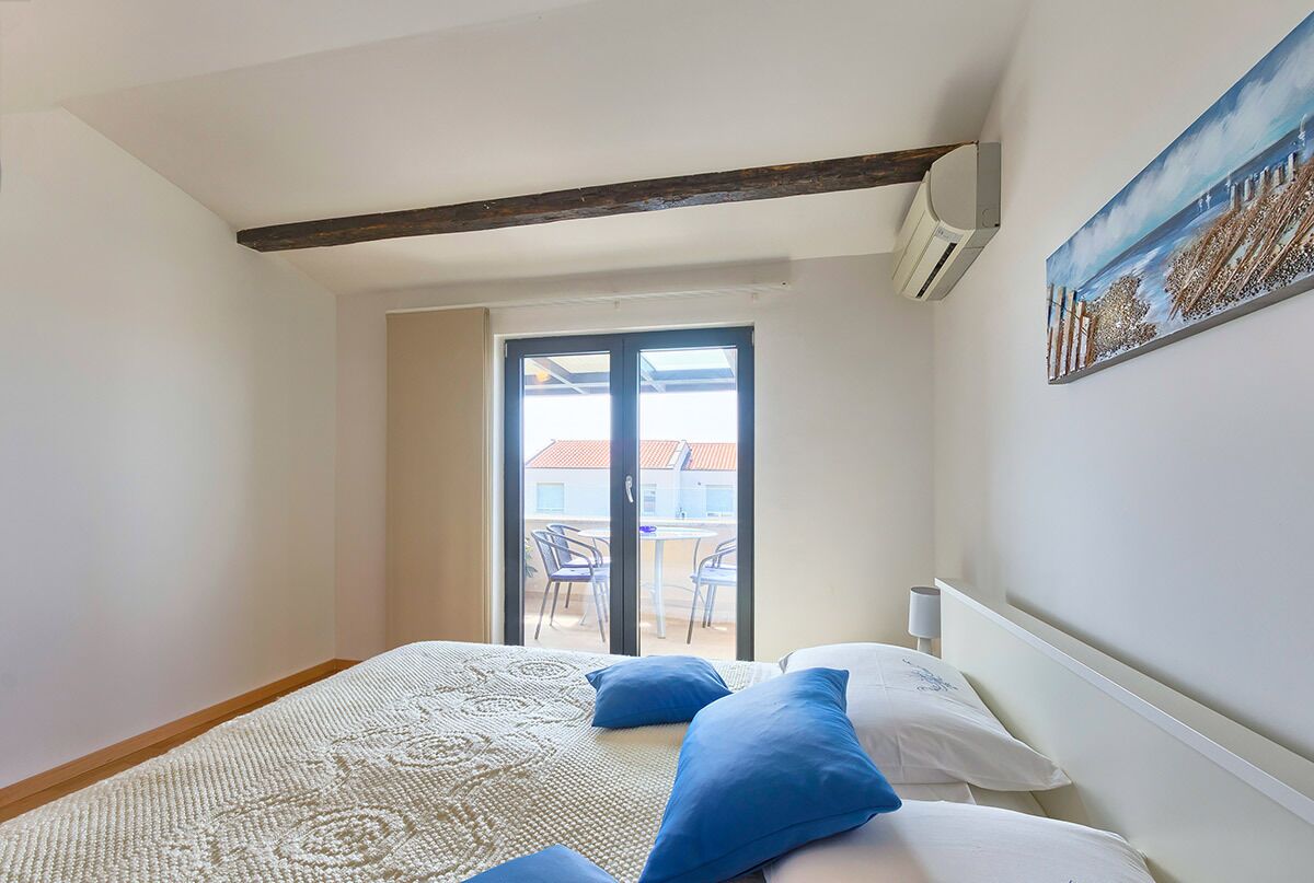 Une chambre à coucher avec un lit, un tableau, une fenêtre et une vue sur l’extérieur.