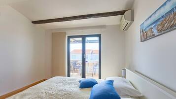 Une chambre à coucher avec un lit, un tableau, une fenêtre et une vue sur l’extérieur.