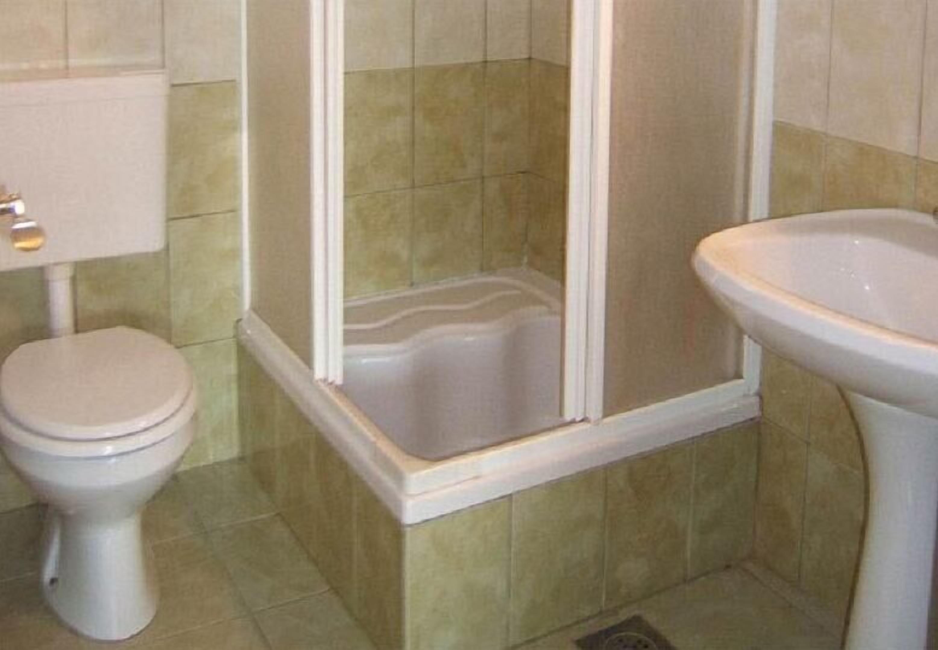 Une salle de bain comprenant des toilettes, un espace douche et un lavabo.