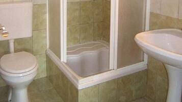Une salle de bain comprenant des toilettes, un espace douche et un lavabo.