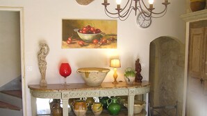 Un comedor con una mesa que exhibe diversos objetos de cerámica, un bodegón de frutas y una araña.