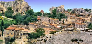 A historic town with stone buildings, terraced rooftops, and a prominent cliff.