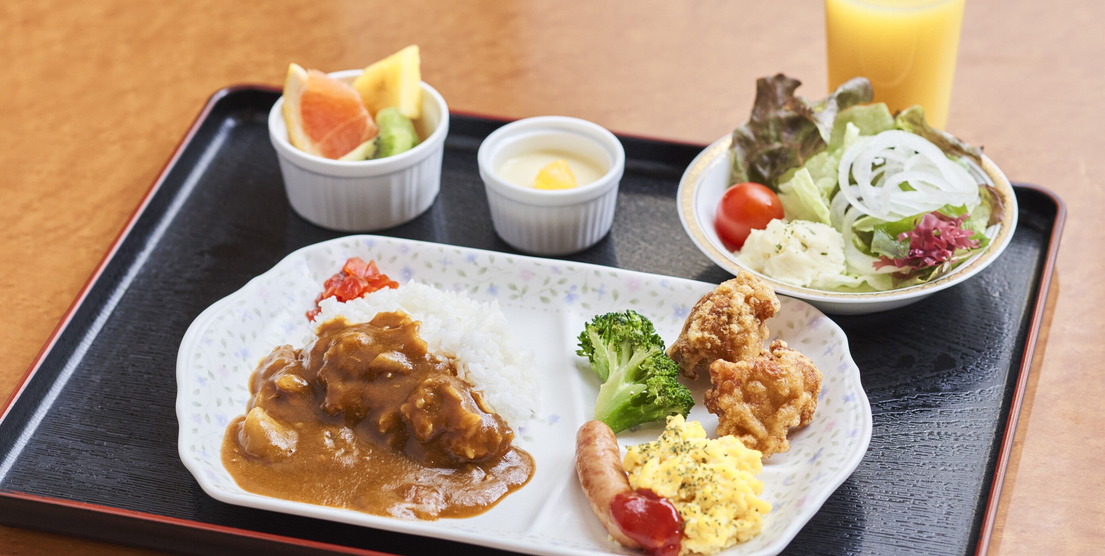 A tray with a plate of curry, fried chicken, rice, and a side salad.