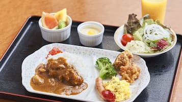 A tray with a plate of curry, fried chicken, rice, and a side salad.