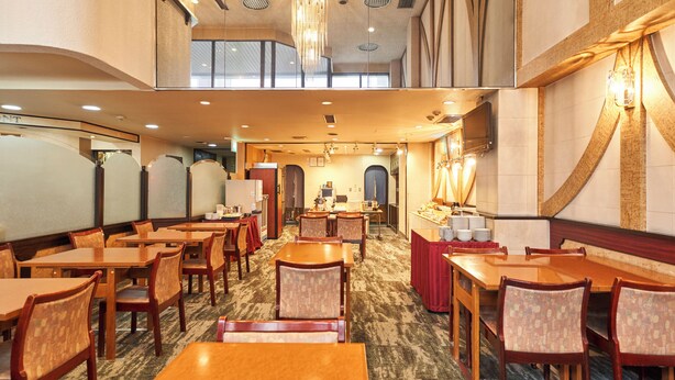 A hotel dining area with multiple wooden tables and chairs, a carpeted floor, and a high ceiling with recessed lighting. - Hotel Paco Obihiro Chuo (Obihiro)