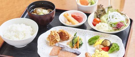 A tray with various dishes including rice, fish, vegetables, and a bowl of soup.