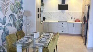 Una cocina moderna con gabinetes blancos, salpicadero de mármol y microondas integrado.
