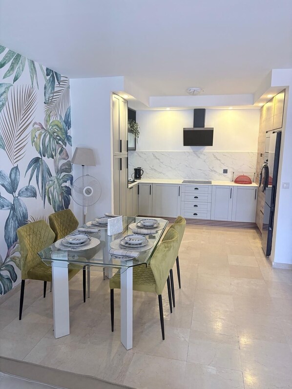Una cocina moderna con gabinetes blancos, salpicadero de mármol y microondas integrado.