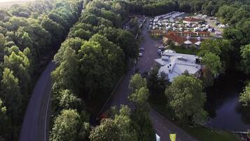 An aerial view of a campground with RV parking, a road, and dense forested hills.