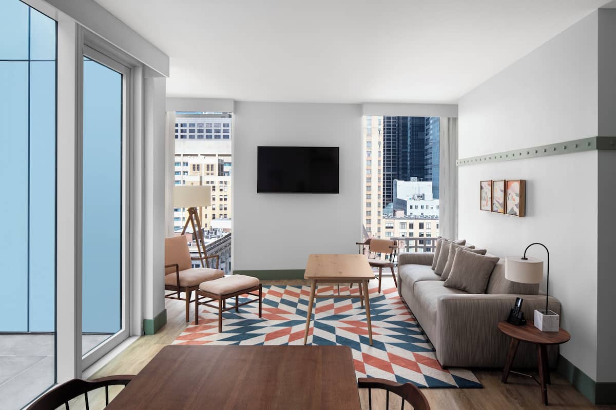 A modern living room with a sofa, chairs, a coffee table, and a TV mounted on the wall.