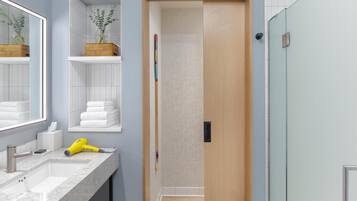 A bathroom with a marble sink, a mirror, a towel rack, and a wooden door.