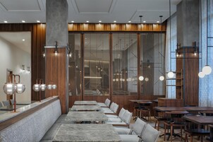 A modern restaurant interior with marble counters, wooden paneling, and multiple seating arrangements.