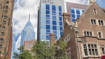 Un hotel con una fachada moderna de vidrio y un edificio clásico de ladrillo en primer plano.