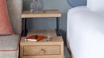 A neatly arranged hotel room with a bed, bedside table, lamp, and a framed picture on the wall.
