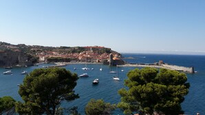 A coastal town with historic buildings, a fortified structure, and boats in the harbor. - Studio Magnifique Vue Mer, Piscine, Climatisation, Terrasse, Parking Couvert (Collioure)