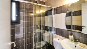 A modern bathroom with a glass-enclosed shower, a toilet, and a sink with toiletries.