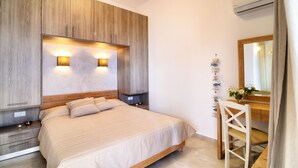 A bedroom with a large bed, wooden headboard, bedside tables, a mirror, and a decorative wall piece.