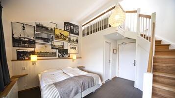 Habitación de hotel con cama, una escalera y cuadros en la pared.