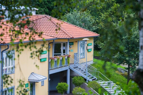 A yellow building with a red-tiled roof, a balcony with flowers, and a staircase leading to the entrance. - Lisebergsbyn Bed & Breakfast (Gothenburg)
