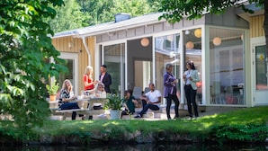 Un espace extérieur moderne, aménagé avec un espace détente, une paroi en verre, une petite fontaine et une terrasse en bois.
