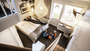 Une chambre avec un grand lit, un bureau et une fenêtre donnant sur l’extérieur.