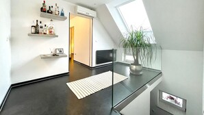 Un intérieur moderne avec une rambarde en verre, une plante en pot et une étagère remplie de bouteilles.