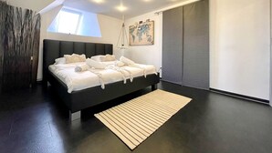 Une chambre moderne avec un grand lit, une œuvre d’art représentant une carte du monde et un placard à portes coulissantes.