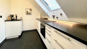 Une cuisine moderne dotée d’une verrière, de meubles blancs et d’un plan de travail noir.
