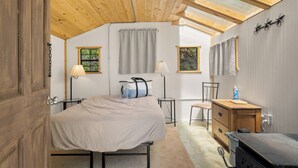 Un dormitorio con cama, lámparas de noche, cómoda, silla y ventana con cortinas.