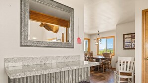 Comedor con techo de madera, un espejo grande y encimera de piedra.