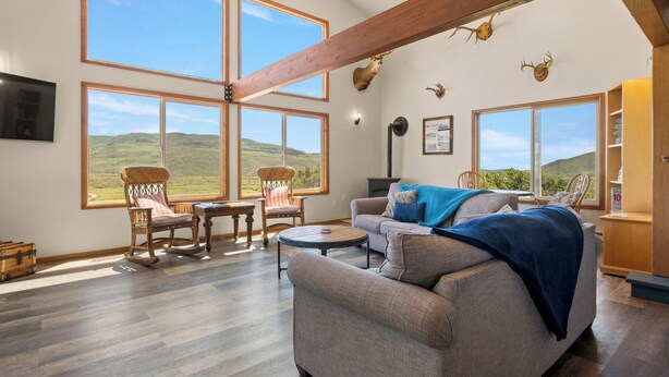 Amplia sala de estar con ventanas grandes, chimenea y decoración rústica que incluye cuernos de ciervo.