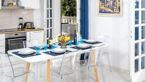 A modern kitchen with white cabinets, a wooden countertop, and a dining area with a white table and clear chairs.