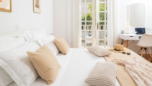 A hotel room with a bed, a desk, and a view of greenery outside.