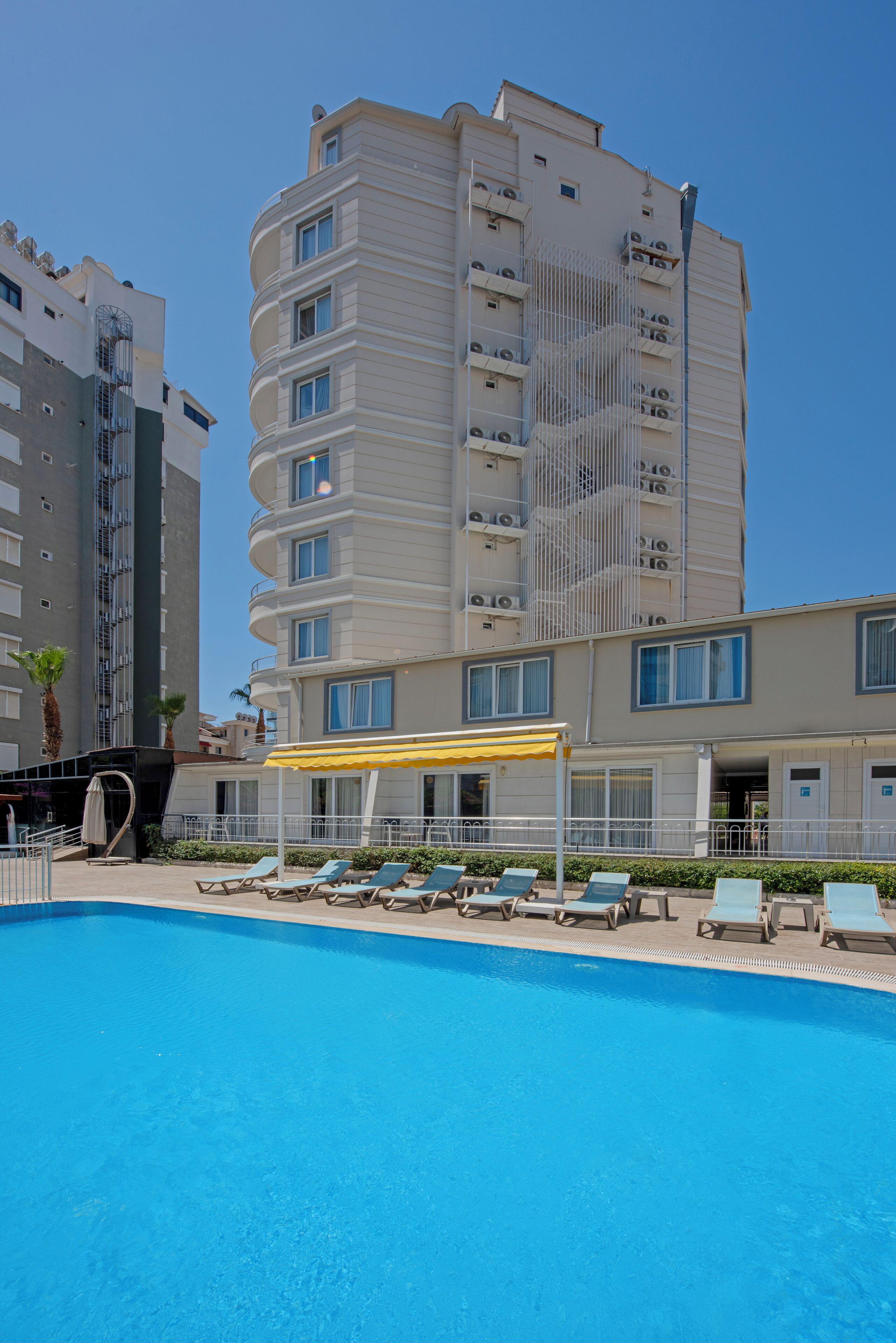 A hotel with a pool area, including lounge chairs and a covered seating area.