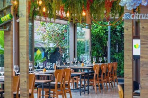 An indoor dining area with wooden tables and chairs, surrounded by glass walls and windows. - Citrus Park Hotel (Konyaalti)