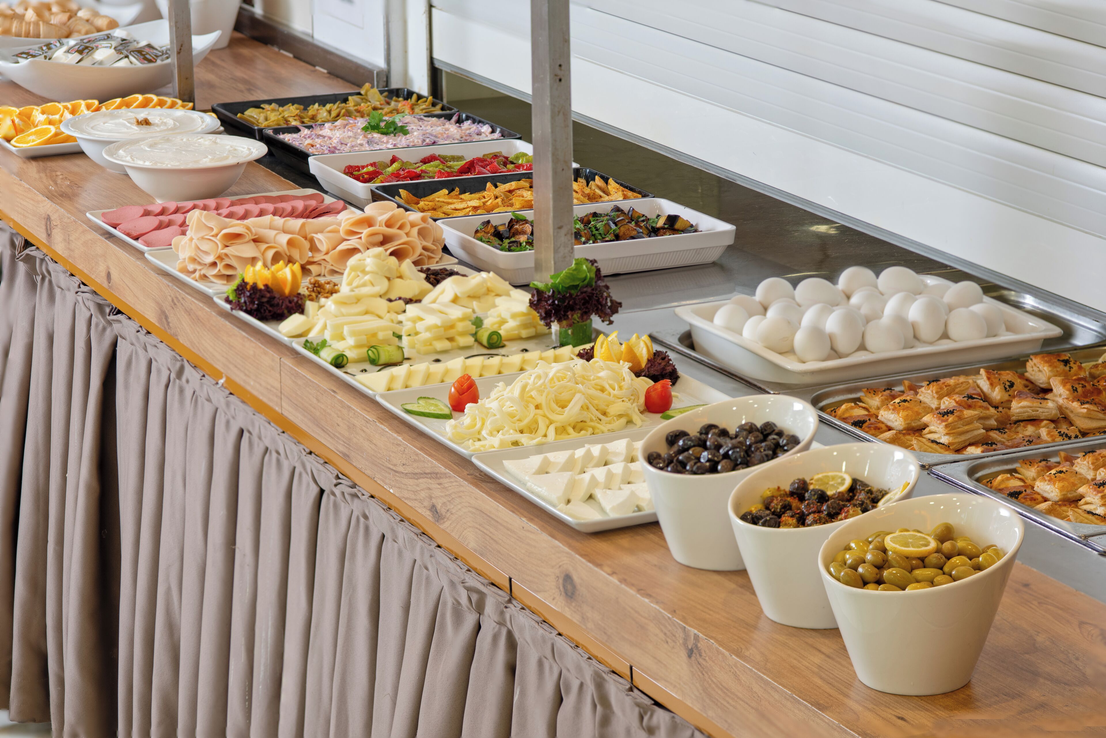 A buffet with various food items including meats, cheeses, and salads.